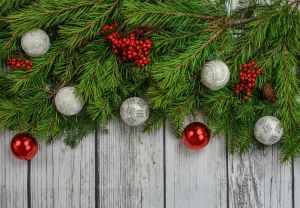 Tannengrün mit Weihnachtskugeln geschmückt, vor einer grauen Bretterwand,
